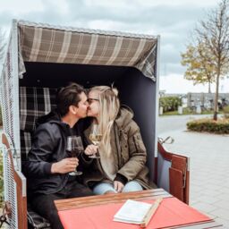 Paar trinkt Wein im Strandkorb bei Sante Weinlounge im Yachthafen Grömitz